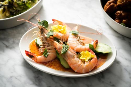 a plate of shrimp and cucumbers on a table at Kimpton Hotel Fontenot by IHG in New Orleans