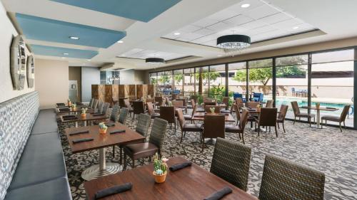 a restaurant with tables and chairs and windows at Crowne Plaza Phoenix Airport - PHX by IHG in Phoenix