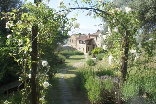 a path through a garden with a house in the background at EcoResort Il Cantico della Natura in Magione