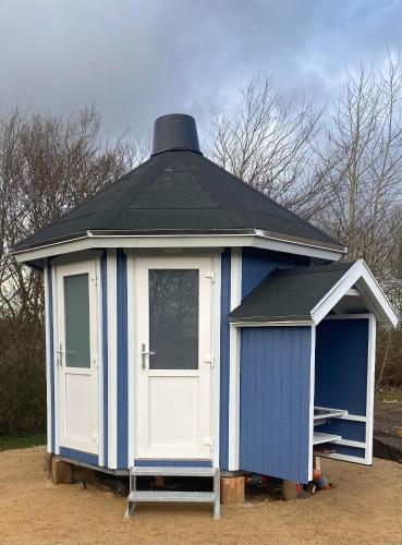 a small blue and white building with a black roof at Kroghs Tiny Houses - Hyttebyen in Grindsted