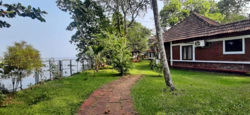 a house on a grassy hill next to a fence at Lovedale Lakeside Homestay in Alleppey