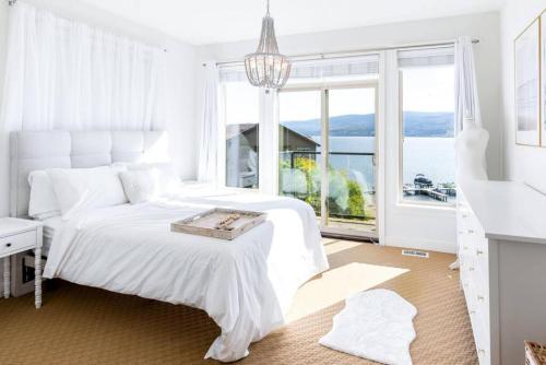 a white bedroom with a bed and a large window at The Beach House at Barona Beach 4301 in West Kelowna