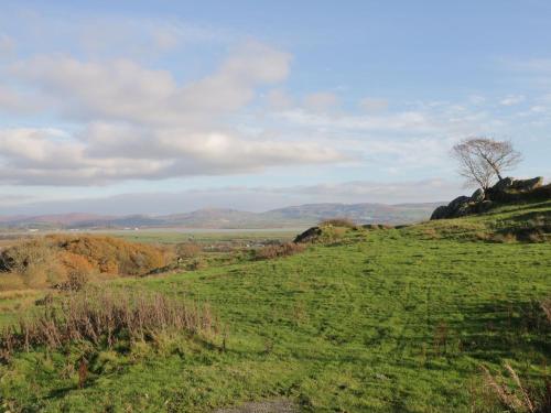 a green field with a tree on a hill at Station View in Soutergate
