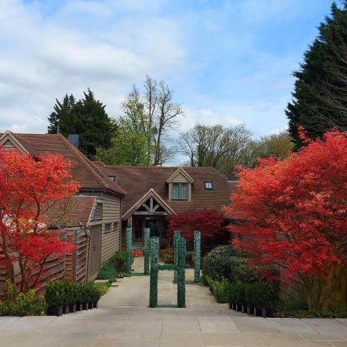 a house with red trees and statues in front of it at Hurley House Hotel in Hurley