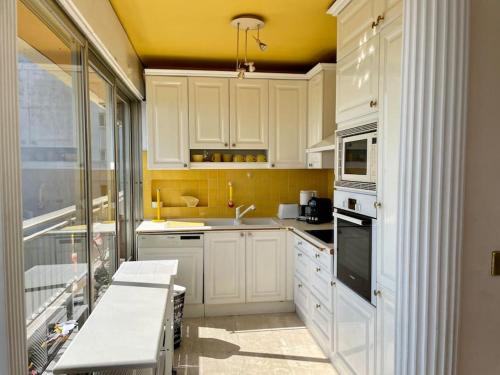 a kitchen with white cabinets and a yellow wall at Magnifique T4 face à la mer, vue panoramique 180° in Roquebrune-Cap-Martin