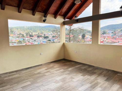 an empty room with two large windows and wooden floors at Hotel Paraiso Real Plus in Mineral del Monte