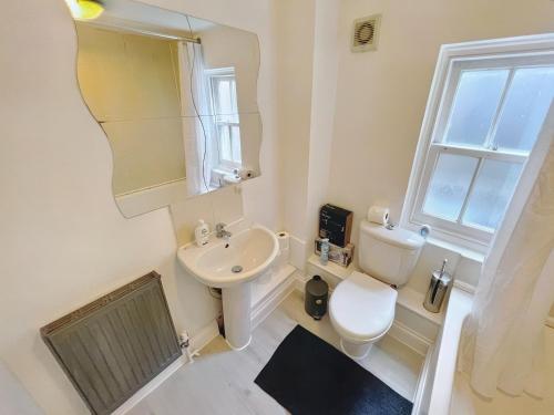 Lovely 2-bedroom serviced apartment Greater London في لندن: حمام مع حوض ومرحاض ومرآة