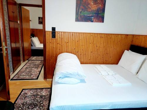 a bedroom with a white bed with a wooden wall at ΔΙΑΜΕΡΙΣΜΑ ΧΩΡΗΤΙΚΟΤΗΤΑΣ ΜΕΧΡΙ 4 ΑΤΟΜΩΝ ΚΕΝΤΡΙΚΑ! in Metsovo
