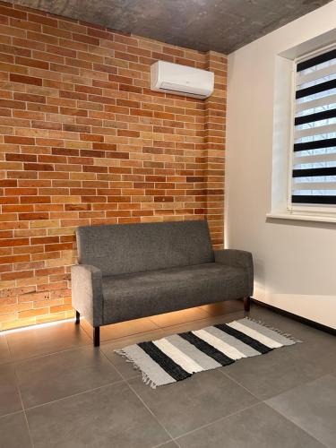 a couch in a room with a brick wall at Loft на Кониського, центр in Dnipro