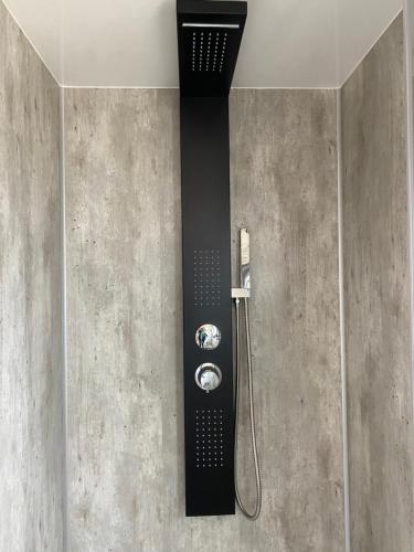 een douche in een badkamer met een zwarte muur bij SeaYou House boat in Offingawier