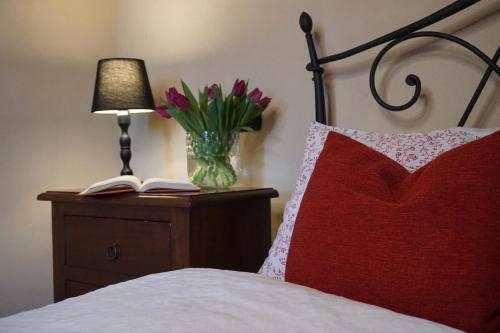 a bed with a red pillow and a vase of flowers at Agritur Maso Carpenè in Rovereto