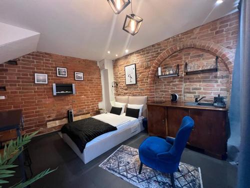 a bedroom with a brick wall with a bed and a blue chair at Apartamenty Prosta - Podmurna in Toruń