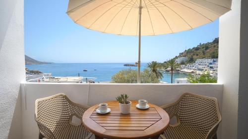 uma mesa de madeira com cadeiras e um guarda-sol numa varanda em Villa Niki em Loutró