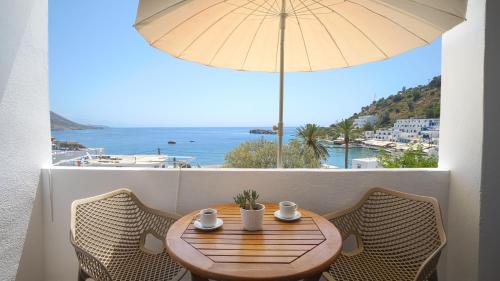 a wooden table with chairs and an umbrella on a balcony at Villa Niki in Loutro
