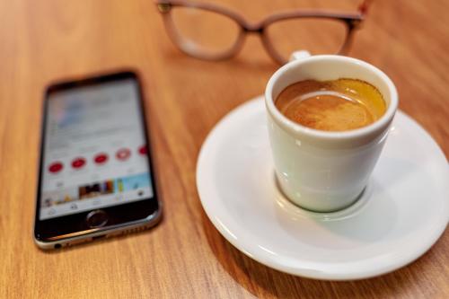 a cup of coffee and a cell phone on a table at ibis Criciuma in Criciúma
