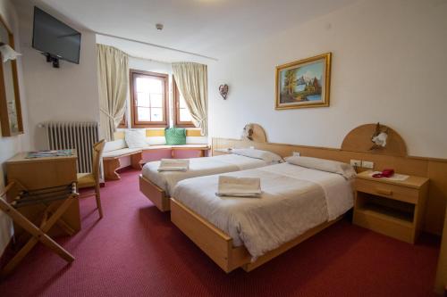 a bedroom with two beds and a flat screen tv at Hotel Edelweiss in Val di Zoldo