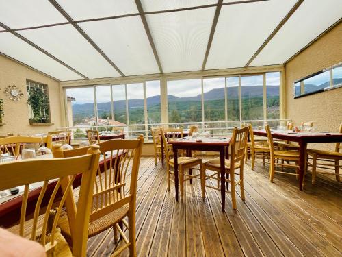 ein Esszimmer mit Tischen, Stühlen und Fenstern in der Unterkunft Auberge de Barret sur Meouge in Barret-sur-Meouge