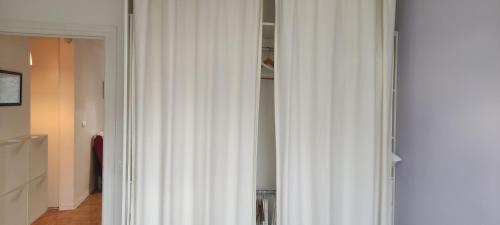 een witte kastdeur met een wit gordijn in een kamer bij 2 pièces 38 M2 Francheville in Francheville