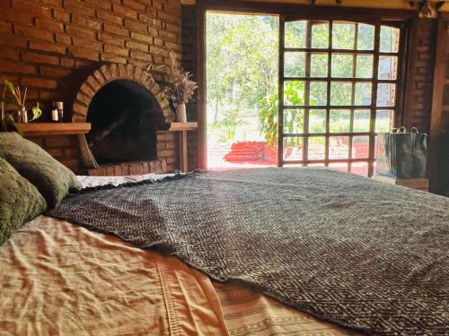 uma cama grande num quarto com uma parede de tijolos em Casa de Campo La Olivia em Eldorado