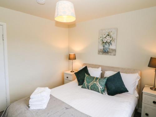 a bedroom with a bed with white sheets and green pillows at Shoemaker's Rest in Beara Peninsula
