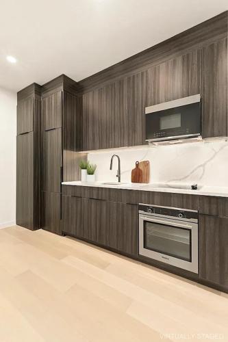 uma cozinha com armários de madeira escura e um lavatório em Designer Duplex near Central Park em Nova York