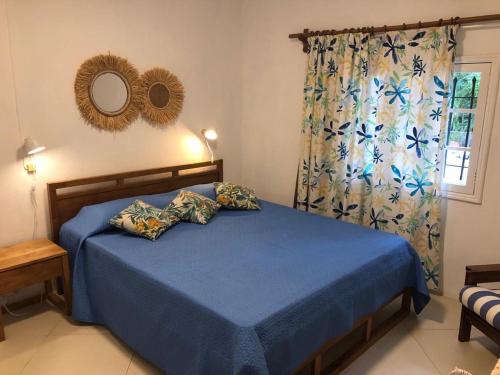 a bedroom with a blue bed with a mirror and a window at Trou d’Eau Douce - Campement pieds dans l’eau in Trou dʼ Eau Douce