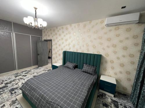 een slaapkamer met een bed met een groen hoofdeinde bij Yakkasaroy Dream House in Tasjkent