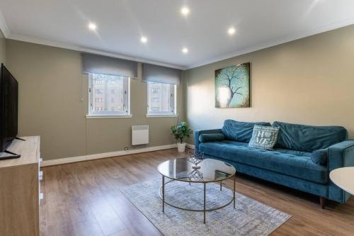 a living room with a blue couch and a table at ** Modern Merchant City 1 BED Apartment with Free Parking ** in Glasgow