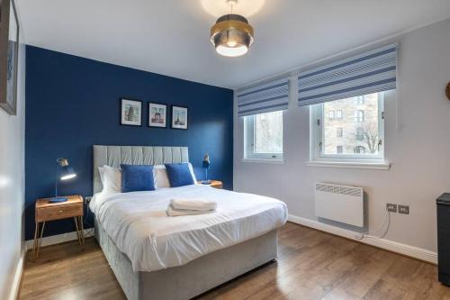 1 dormitorio con paredes azules y 1 cama con almohadas azules en ** Modern Merchant City 1 BED Apartment with Free Parking **, en Glasgow