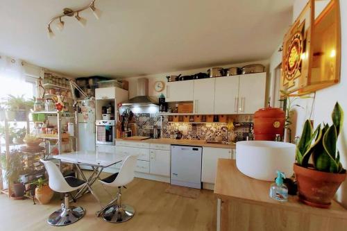 une cuisine avec des armoires blanches et une table et des chaises dans l'établissement T2 cosy à la plage, terrasse vue sur mer et parking privatif, à Narbonne