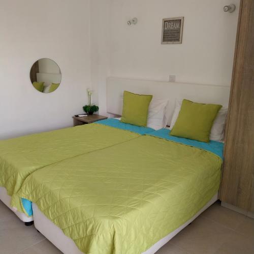 a bedroom with a bed with green sheets and a mirror at Chicos Studios in Ayia Napa