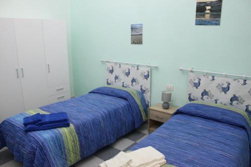 Casa Vacanze Nonna Franca في كابراس: سريرين في غرفة بجدران زرقاء