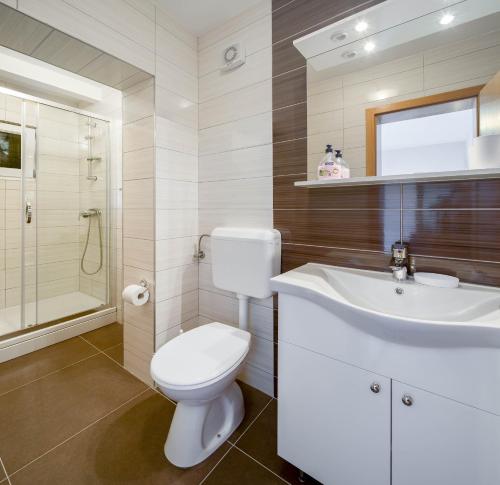 bagno con servizi igienici bianchi e lavandino di Villa Adriatica Excelsior - Beachfront Retreat a Stanići