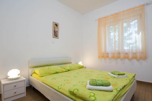 Schlafzimmer mit einem Bett mit grüner Bettwäsche und einem Fenster in der Unterkunft Villa Adriatica Excelsior - Beachfront Retreat in Stanići