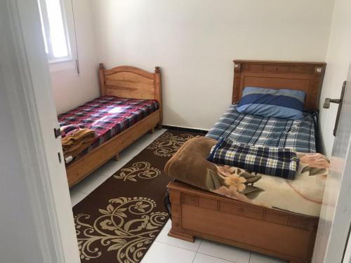une petite chambre avec deux lits et une fenêtre dans l'établissement Appartement Familial en face le grand stade de tanger, à Tanger