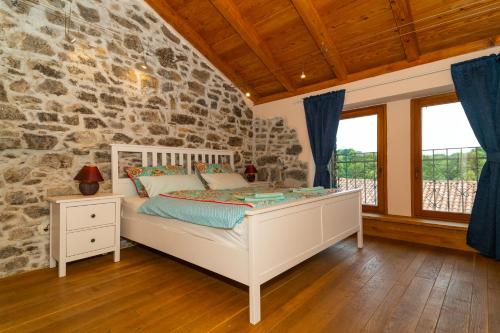 a bedroom with a bed and a stone wall at VILLA SALVIA - Holiday house with pool - in Jurdani