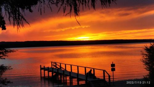a person sitting on a dock on a lake at sunset at komf.Ferienwohnung Elisabeth (1.Stock) in Weilheim, m.Garten, zwischen München u. Garmisch-P. in Weilheim in Oberbayern
