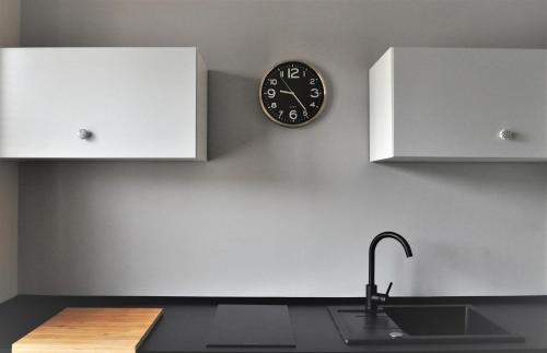 a clock on the wall above a kitchen counter at Apartament Śródmieście Krosno in Krosno