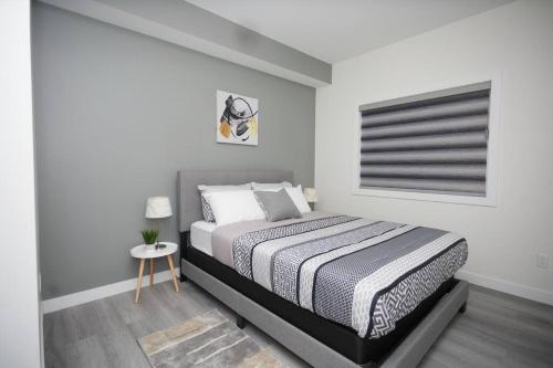 a white bedroom with a bed and a table at Comfortable home near airport in Winnipeg