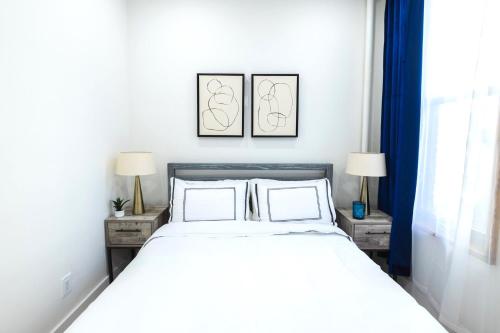 ein Schlafzimmer mit einem weißen Bett und zwei Nachttischen in der Unterkunft 317-3D I NEW Modern 1BR W&D Walk to Central Park in New York
