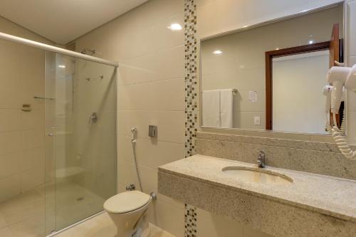 a bathroom with a toilet and a sink and a shower at Hotel Fredy in Águas de Lindoia