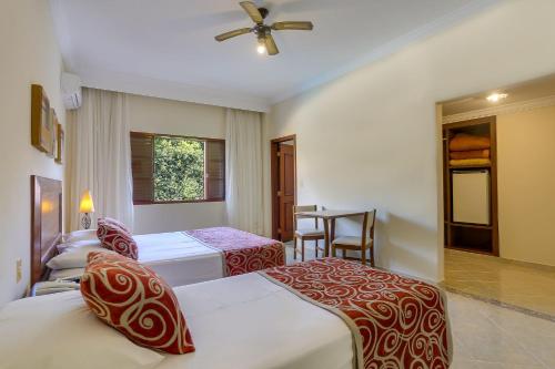 a hotel room with three beds and a table at Hotel Fredy in Águas de Lindoia