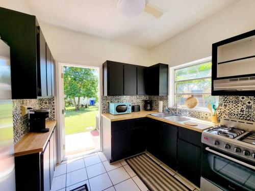 een keuken met zwarte kasten en een groot raam bij LITTLE HAVANA/CALLE OCHO 3 - BEST APARTMENT in Miami
