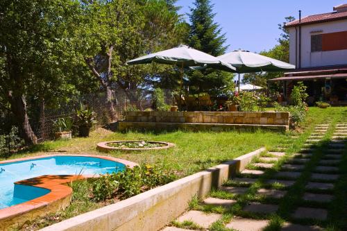 einen Hinterhof mit Pool und Sonnenschirm in der Unterkunft Villa Luxury nel Bosco in Castelbuono