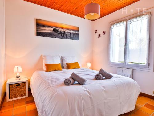 Un dormitorio con una gran cama blanca con almohadas. en Le petit havre de paix Longevillai, en Longeville-sur-Mer