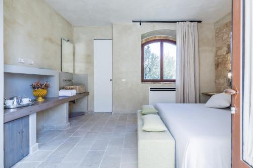 a bedroom with a white bed and a kitchen at Casa Vendicari Boutique Hotel in Noto