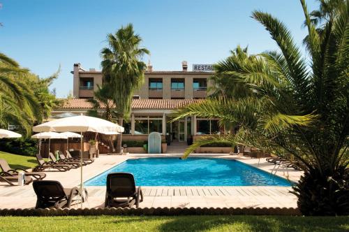 une piscine avec chaises et parasols devant un immeuble dans l'établissement Promotel, à Carros