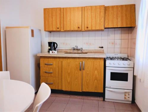 una pequeña cocina con armarios de madera y refrigerador blanca. en Departamento en Mendoza para Linda Estadía en Mendoza