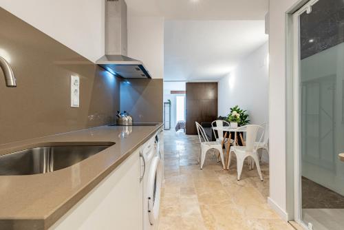 eine Küche mit einem Waschbecken und einem Tisch mit Stühlen in der Unterkunft Apartament Confort en Barri Port Maritim in Tarragona