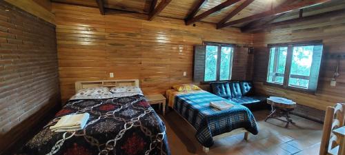 a room with two beds and a bench in a cabin at Cabaña La Vía Láctea in El Pacífico